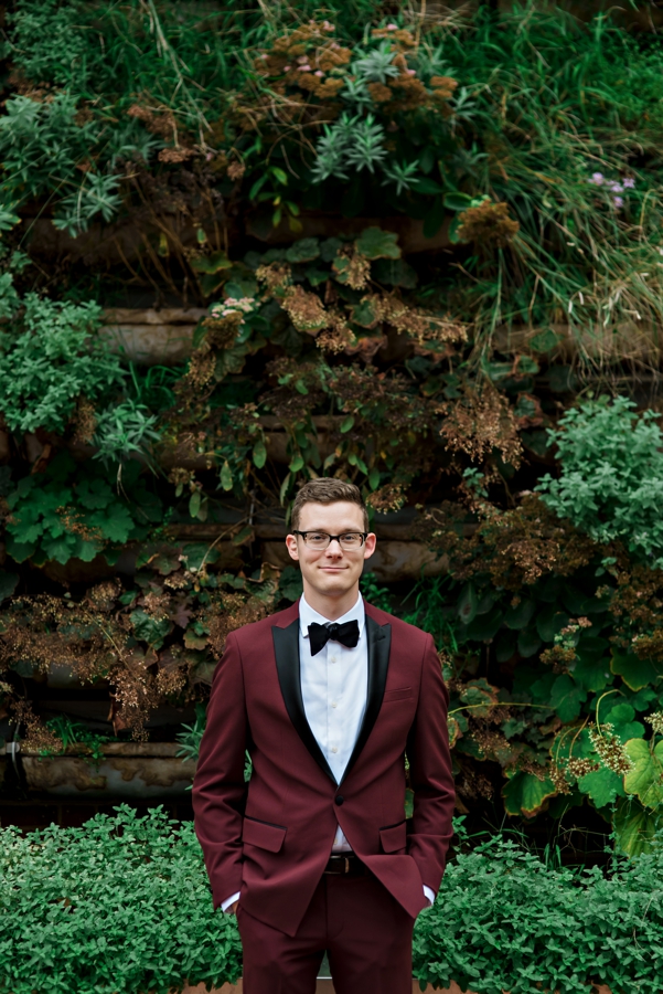 A groom in front of a garden wall in Philadelphia.